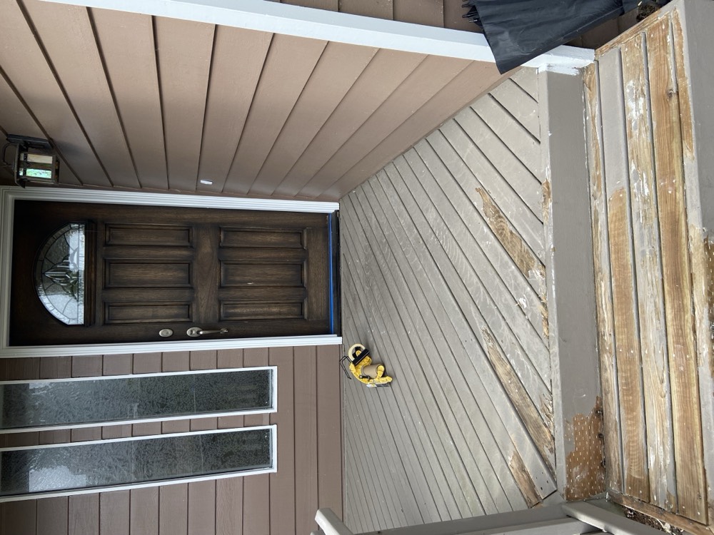Worn front porch with faded decking and dark entry door