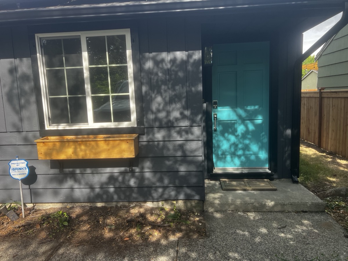 Entry door painted teal against dark charcoal siding