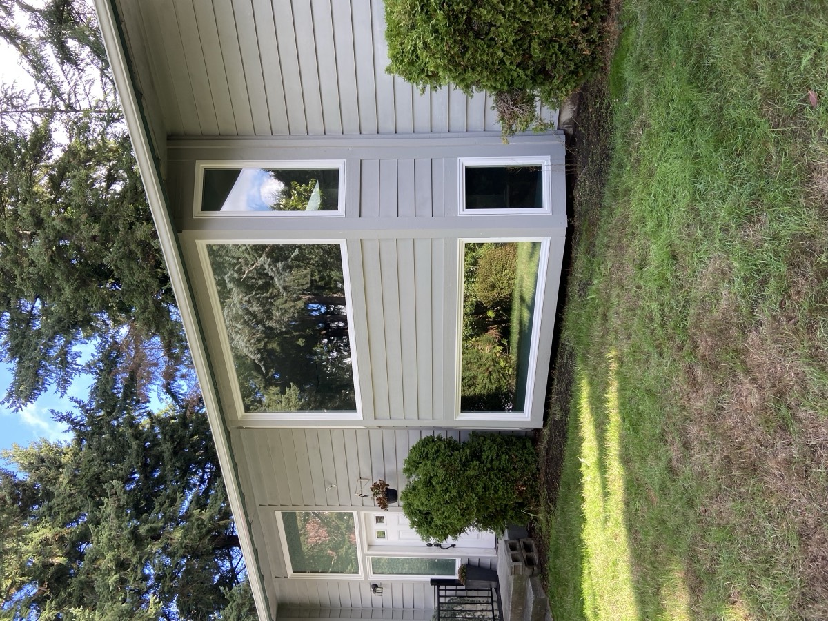Repainted mid-century home exterior in sage green with white window trim